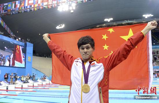 资料图：2012伦敦奥运会男子1500米自由泳决赛，中国选手孙杨以14分31秒02的成绩夺得冠军，这也是中国代表团本届奥运会上取得的第24枚金牌。图为孙杨披国旗庆祝夺冠。记者 廖攀 摄