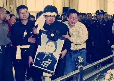 ​2004年，任长霞葬礼的现场，儿子抱着遗像泣不成声，数万群众送行